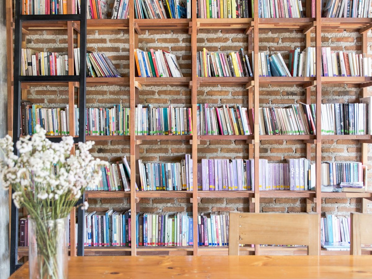 Professora e alunos a consultar livros numa biblioteca escolar